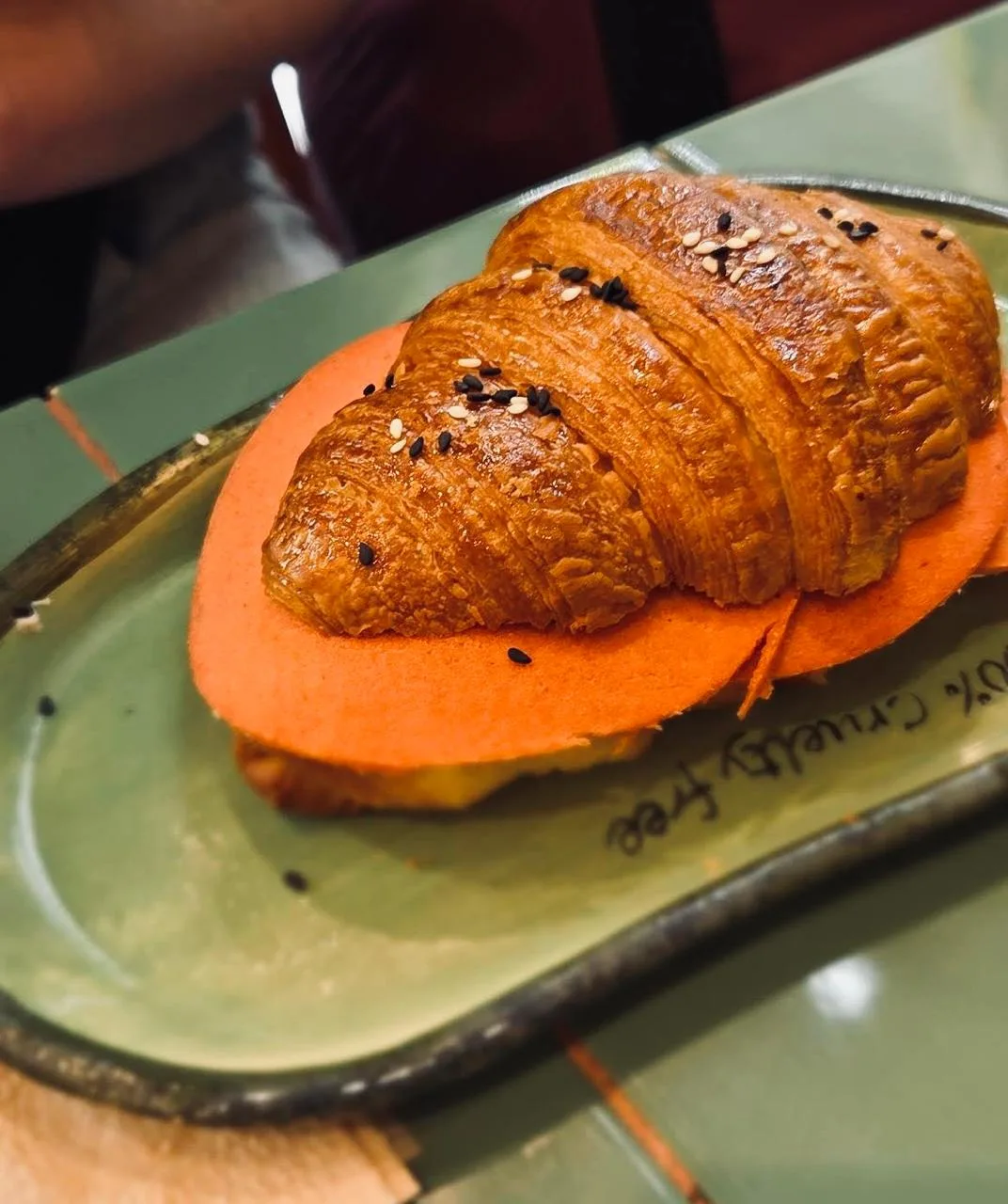 Croissant vegano con láminas de queso vegetal y semillas en plato “100% cruelty free”