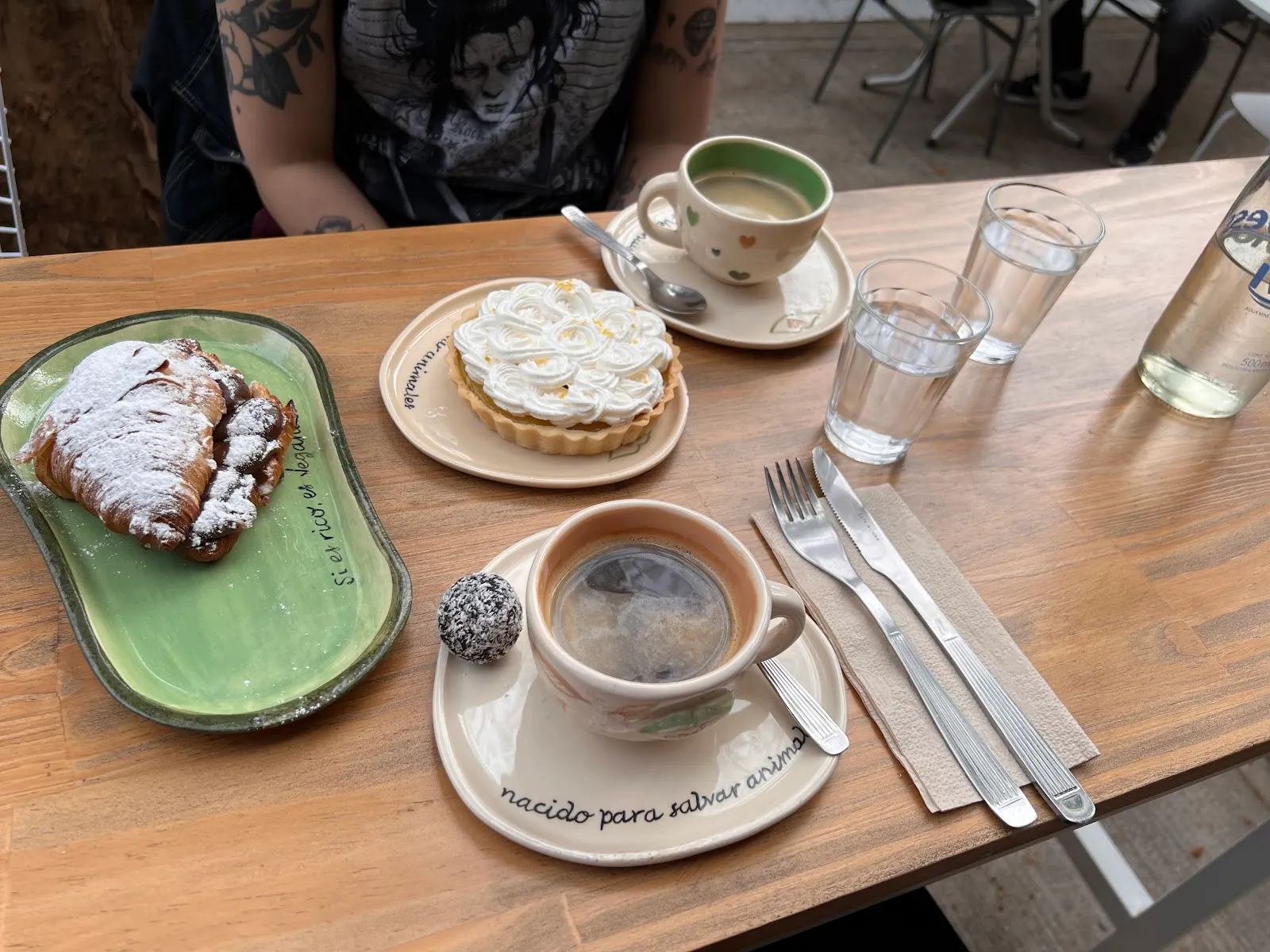 Brunch vegano: tarta, medialuna y café con leche vegetal en mesa de madera